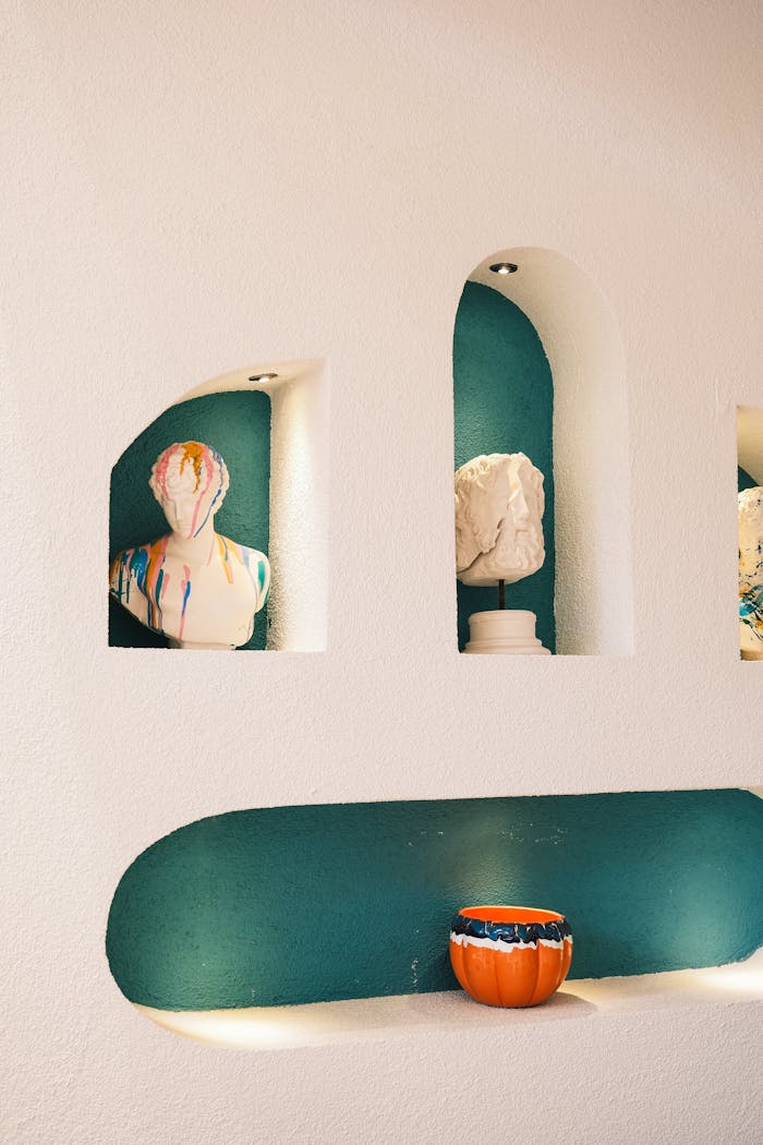 Modern interior featuring colorful busts and artistic vases in wall niches, elegantly lit.