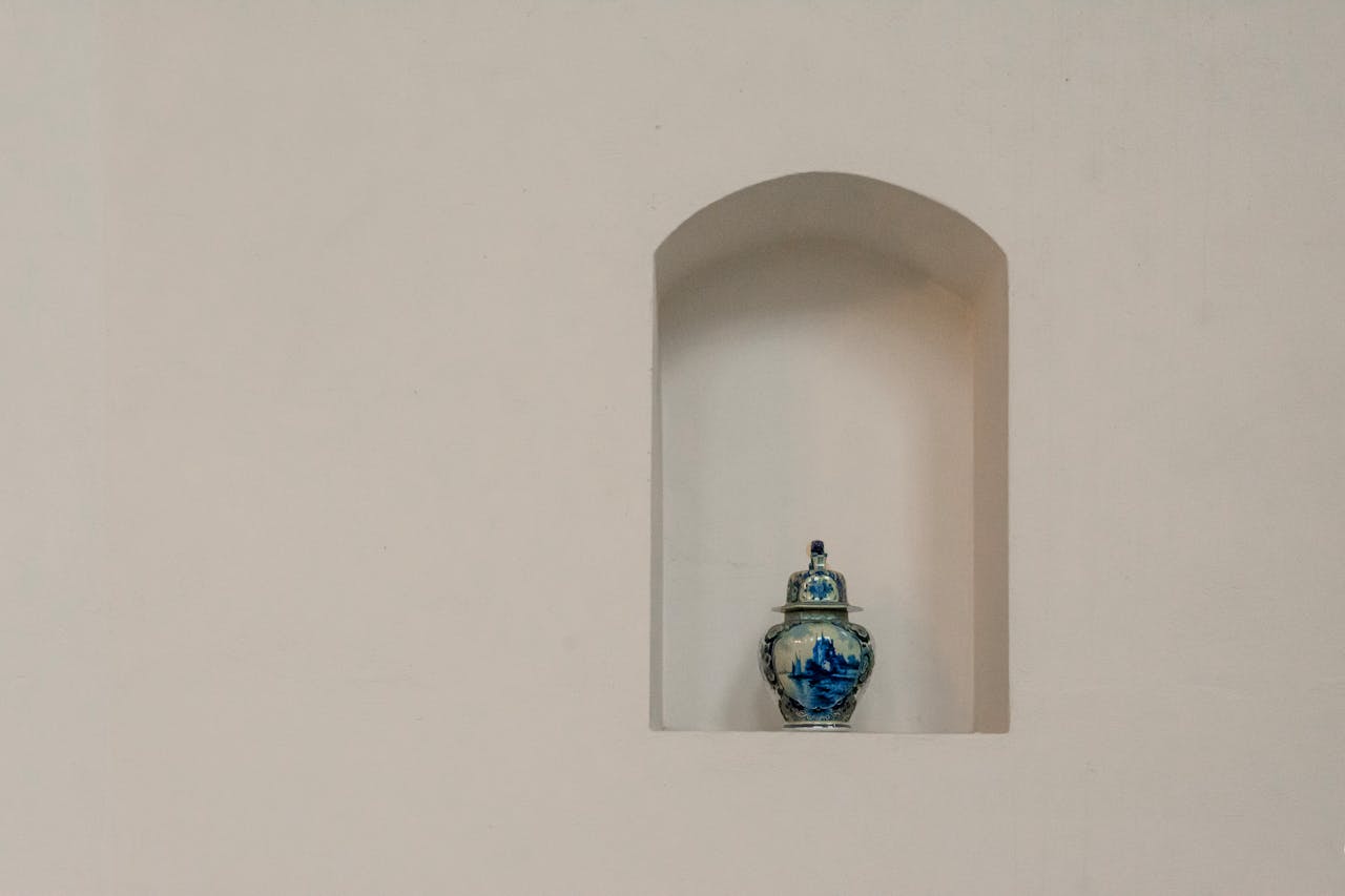 Elegant blue porcelain vase displayed on a minimalist white wall shelf with ample copy space.